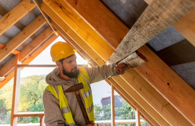 Charpentier professionnel travaillant sur une charpente de toiture en bois